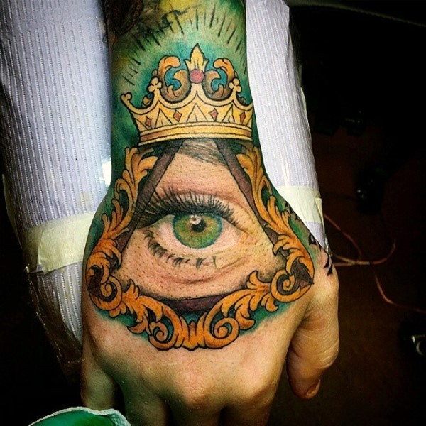 Usual illustrative style colored hand tattoo of human eye in pyramid and crown