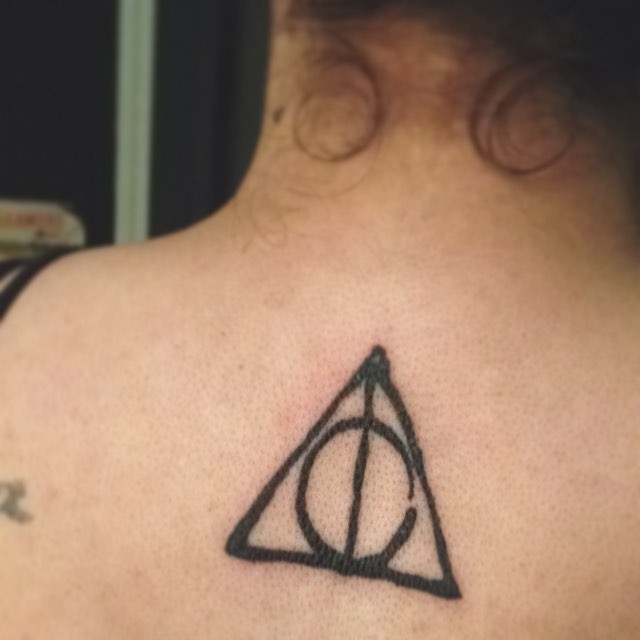 Usual little black ink triangle tattoo on upper back