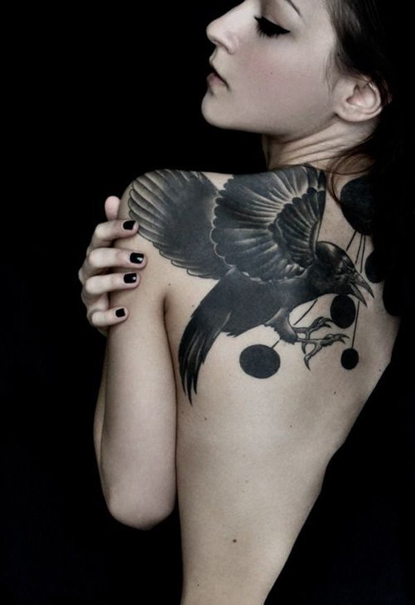 Üblich gemalte schwarze Krähe Tattoo am oberen Rücken mit schwarzen Kreisen