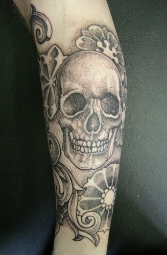 Tatuaje en el antebrazo,
cráneo simple gris y flores diferentes