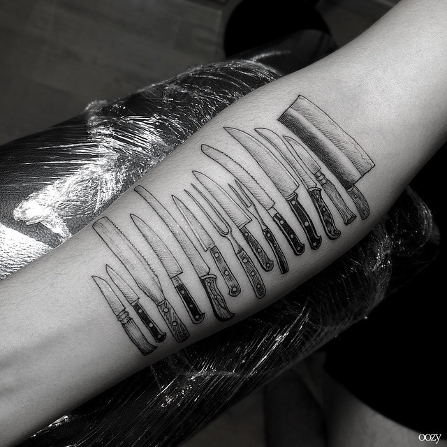 Variety of professional kitchen knives tattoo on forearm