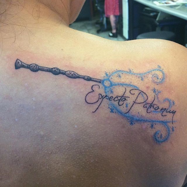 Very beautiful designed colored on shoulder tattoo of magic stick and lettering