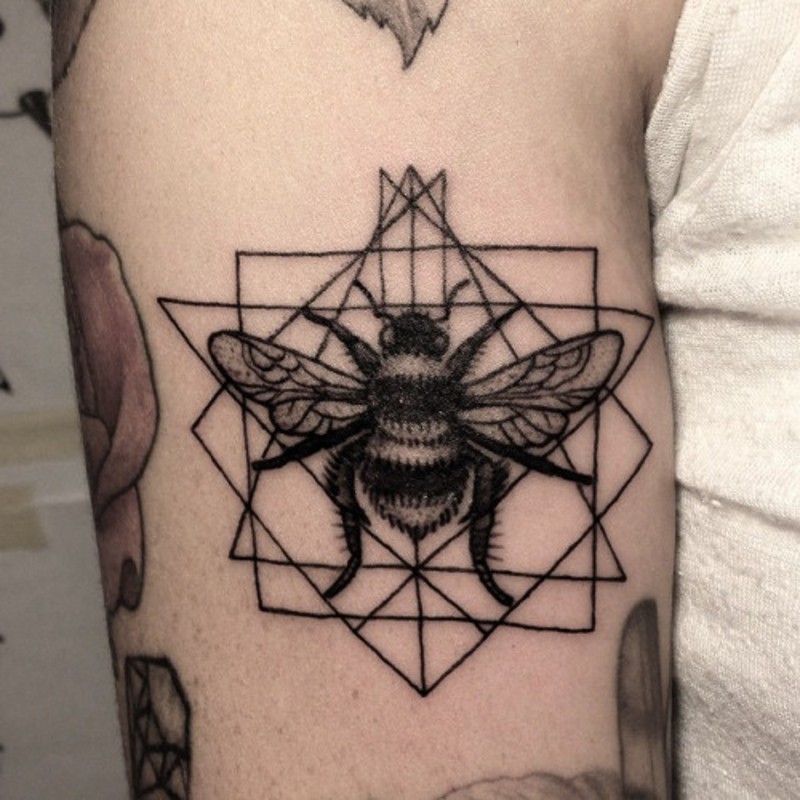 Very detailed natural looking black and white bee tattoo on arm stylized with various geometrical ornaments