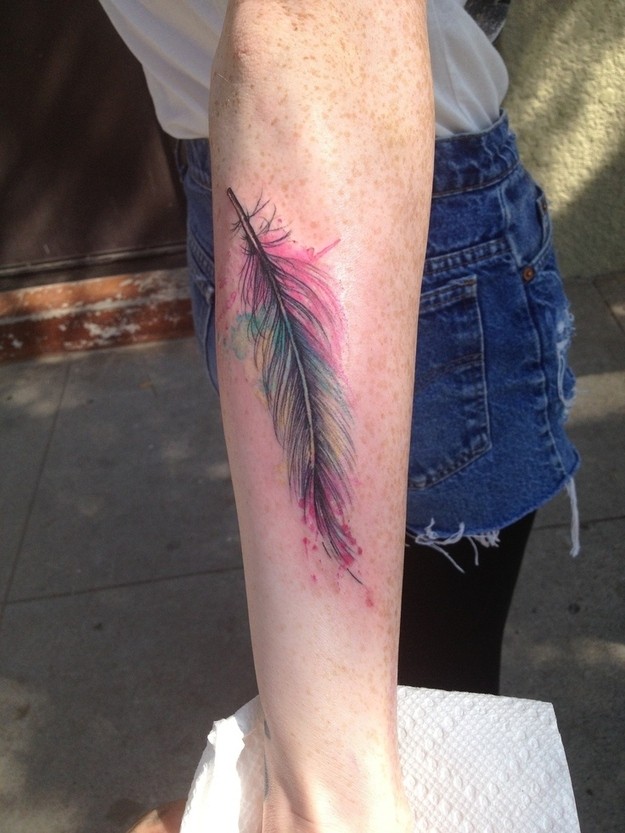 Very realistic detailed multicolored little feather tattoo on arm