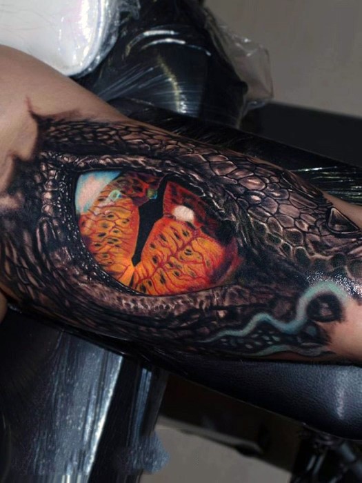Very realistic looking amazing detailed and colored dragon eye tattoo on arm