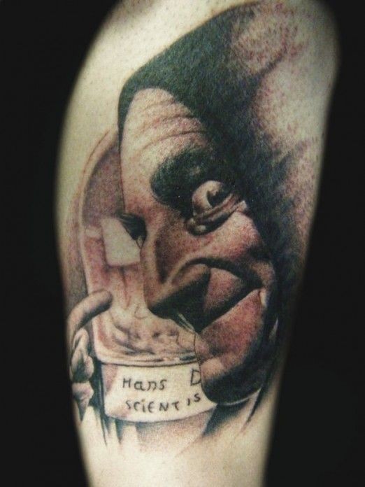 Sehr realistisch aussehender schwarzweißer gruseliger Mann mit Schriftzug Tattoo am Bein