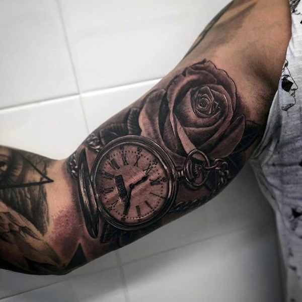 Very realistic looking black and white old clock with flower tattoo on arm