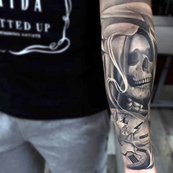 Very realistic looking black ink mystical skull tattoo on forearm with old clock