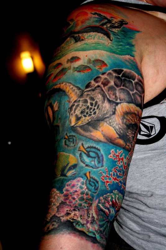 Very realistic looking colored big turtle with fishes underwater tattoo on sleeve