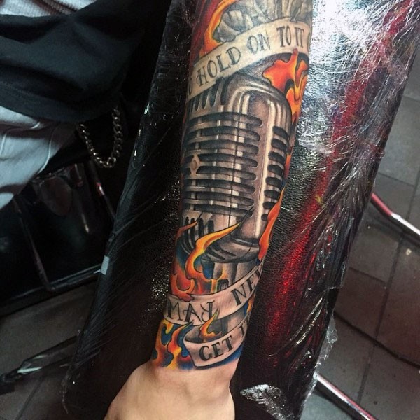 Very realistic looking colored microphone in flames with lettering tattoo on arm