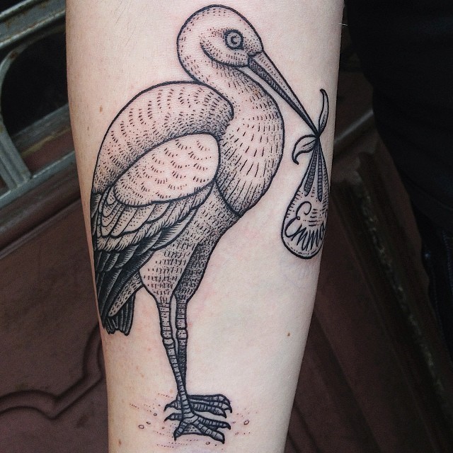 Vintage black and white big stork with little back tattoo on forearm stylized with lettering