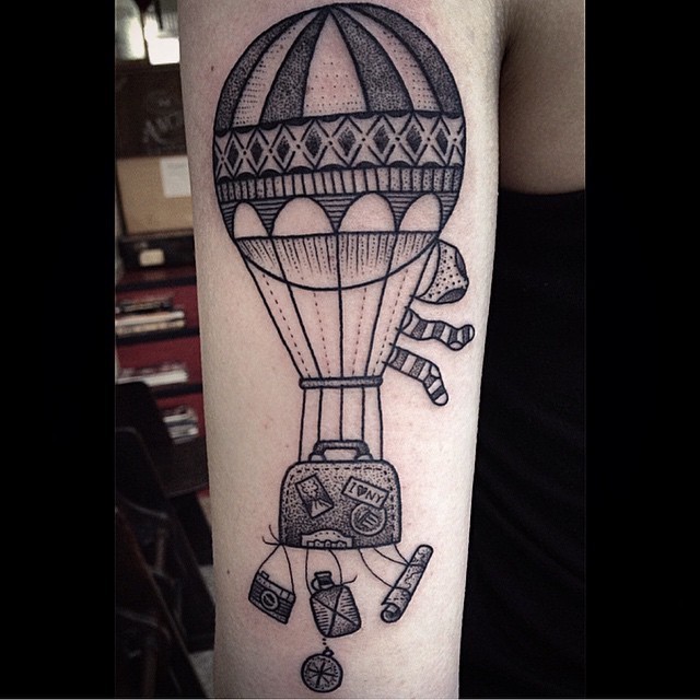 Vintage black ink flying balloon tattoo on arm stylized with clothes