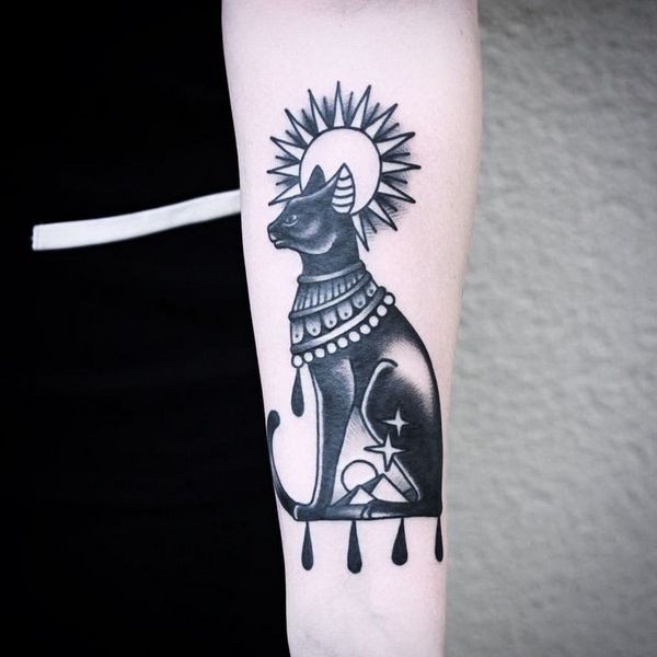Vintage style black ink Egypt cat tattoo on forearm with sun ad stars