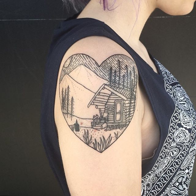 Vintage style black ink heart shaped tattoo on shoulder with old house in mountain forest