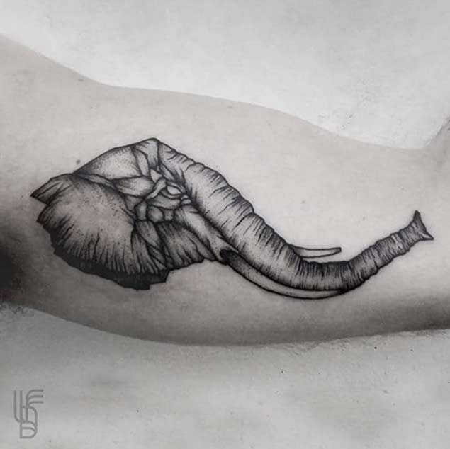 Vintage style black ink little elephant head tattoo on arm muscle