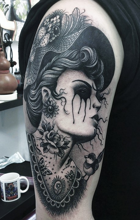 Vintage style black ink shoulder tattoo of crying woman with big hat and flowers