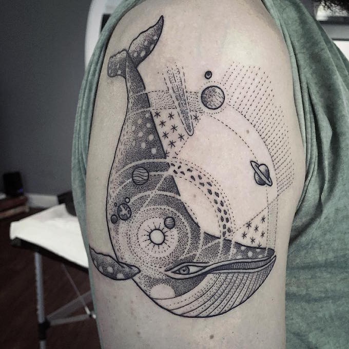 Vintage style black ink whale tattoo on shoulder combined with solar system