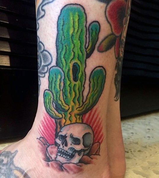 Vintage style colored ankle tattoo of big cactus with human skull