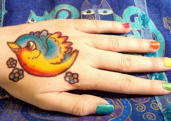 vivaci colori piccolo uccellino su mano tatuaggio