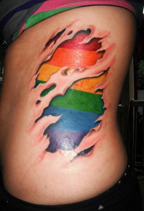 Vivid colors rainbow under skin rip tattoo on ribs