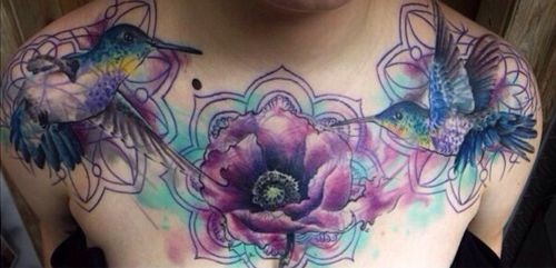 Watercolor hummingbird hovering near a flower tattoo on chest