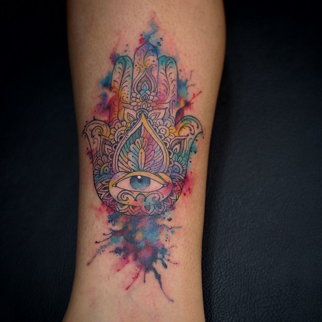 Watercolor like little colored Hamsa hand tattoo on forearm