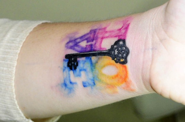 Watercolor love with black key tattoo on wrist