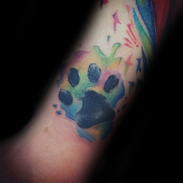 Watercolor style colored arm tattoo of small animal paw print
