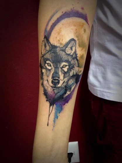 Tatuaggio dell&quotavambraccio colorato in stile acquerello del lupo con la luna