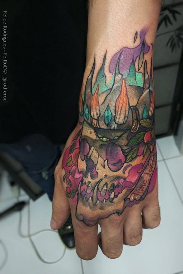 Watercolor style colored hand tattoo of king skull with flames and lettering