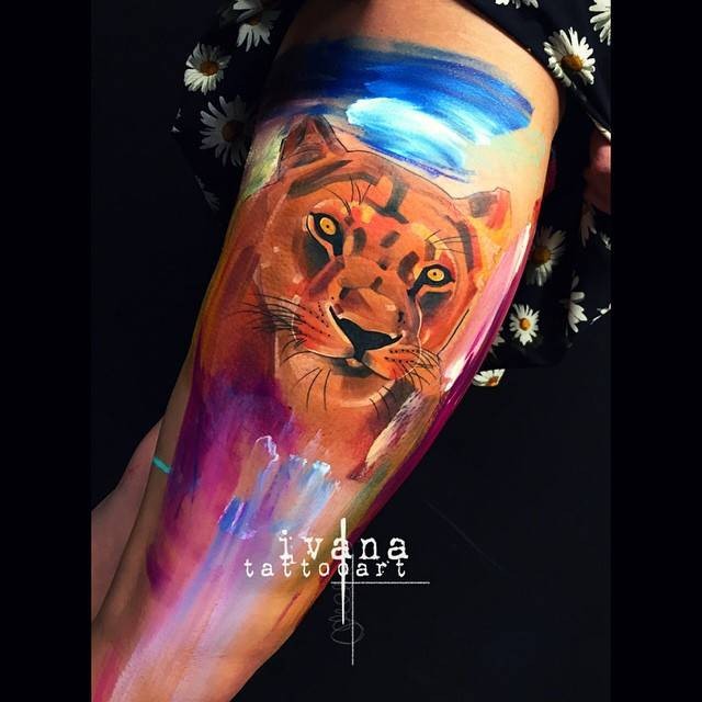 Watercolor style colored thigh tattoo of lion