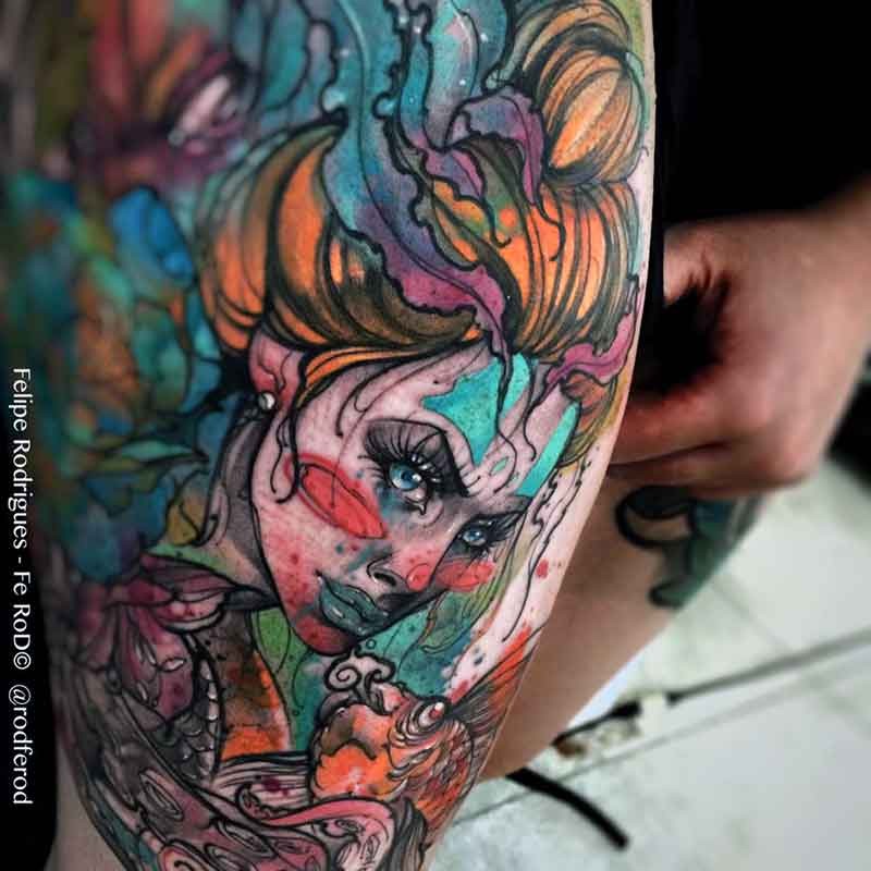 Watercolor style colored thigh tattoo of strange looking woman with fishes