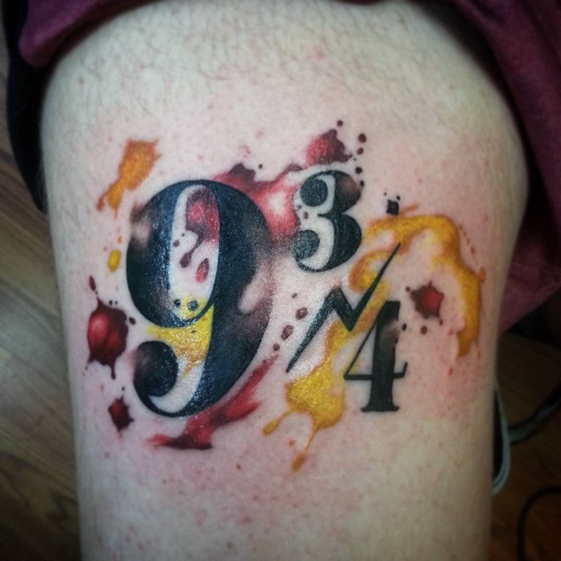 Watercolor style colorful black ink numbers tattoo on thigh