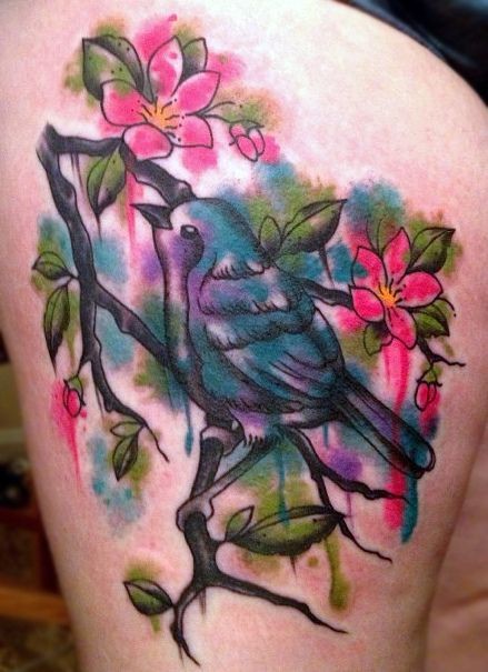 Watercolor style multicolored thigh tattoo of bird and blooming tree