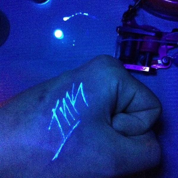 Tatuaje en la mano,  inscripción corta de tinta ultravioleta
