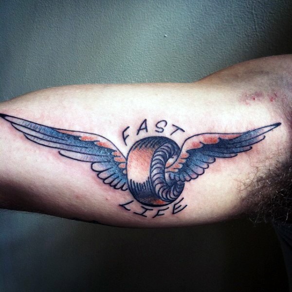 Winged wheel colored old school style tattoo on biceps with black ink lettering