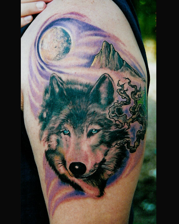 Tatuaggio colorato sul deltoide la faccia del lupo & il paesaggio