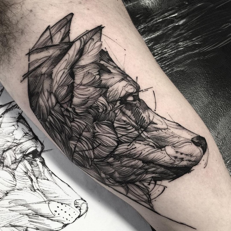 Wolf's head detailed black ink tattoo on biceps in engraving style