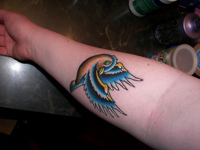 Farbenfroher Spatz Tattoo am Unterarm der Frau