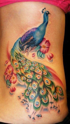 Wonderful colored realistic looking big peacock tattoo on back