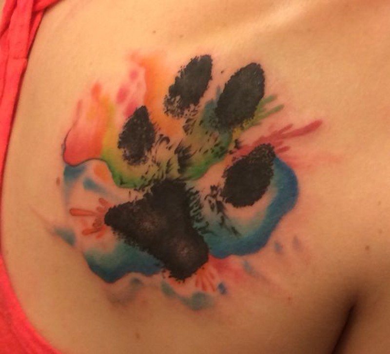 Tatuaje en el hombro,
huella negra de un perro con mancha abigarrada