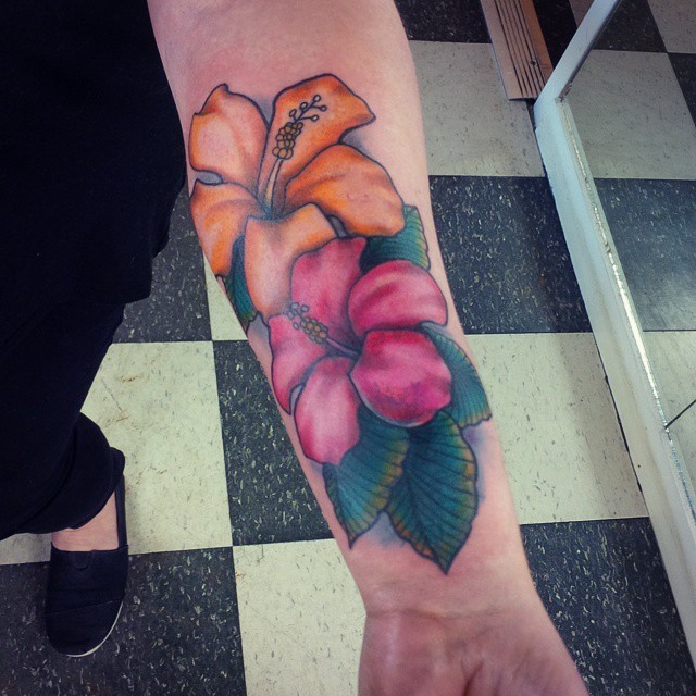 Yellow and pink hibiscus flowers Hawaiian themed forearm tattoo with pale blue haze