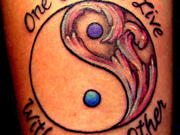 Tatuaje en el brazo, yin yang y inscripción