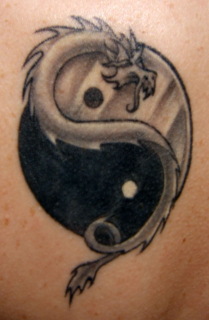 Tatuaje en la espalda, yin yang y un dragón en la mitad