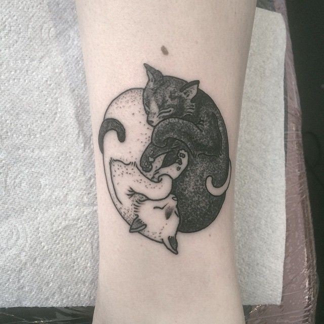 Yin yang symbol shaped tattoo of sleeping black and white cats
