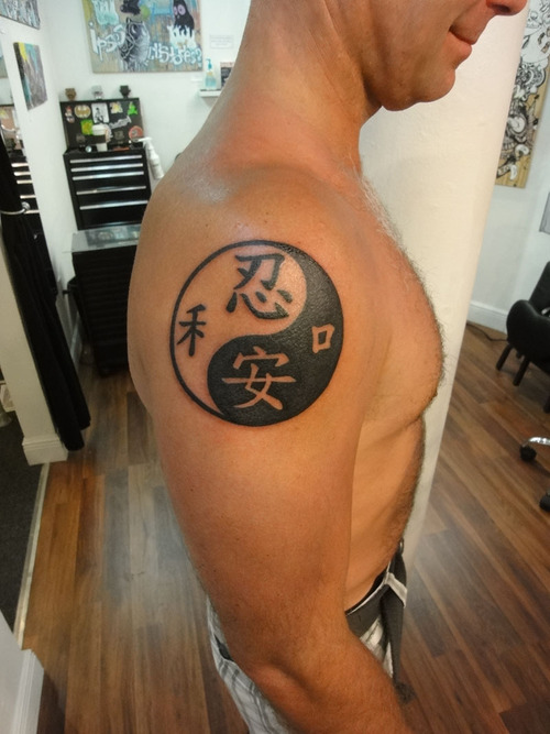 Tatuaje en el brazo, yin yang y jeroglíficos